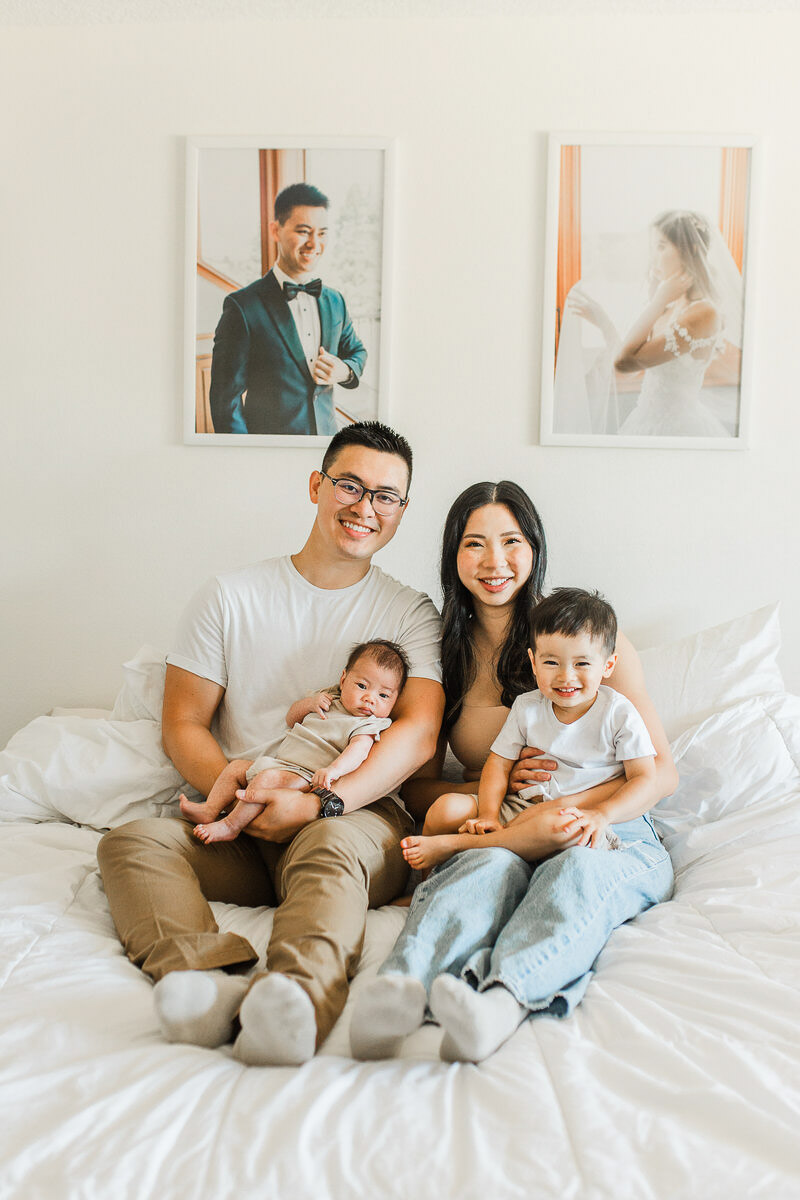 A family snuggling in their home with their toddler and newborn.