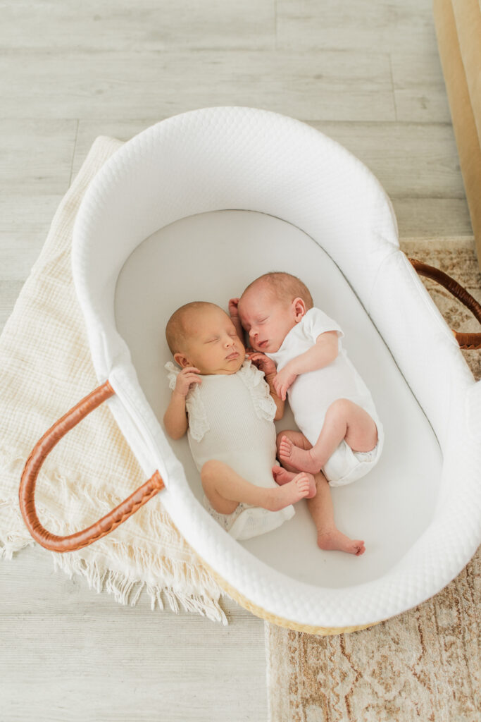 Twin newborn photo session in studio in a moses basket with a cozy neutral blanket underneath.