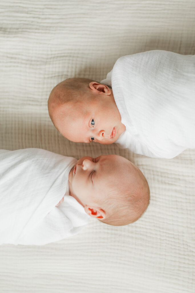 Photo of newborn twin babies swaddled next to each other.
