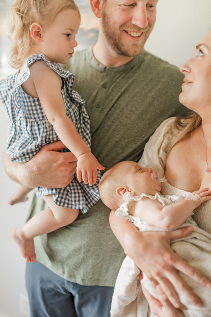 parents hold their two little kids and smile at each other