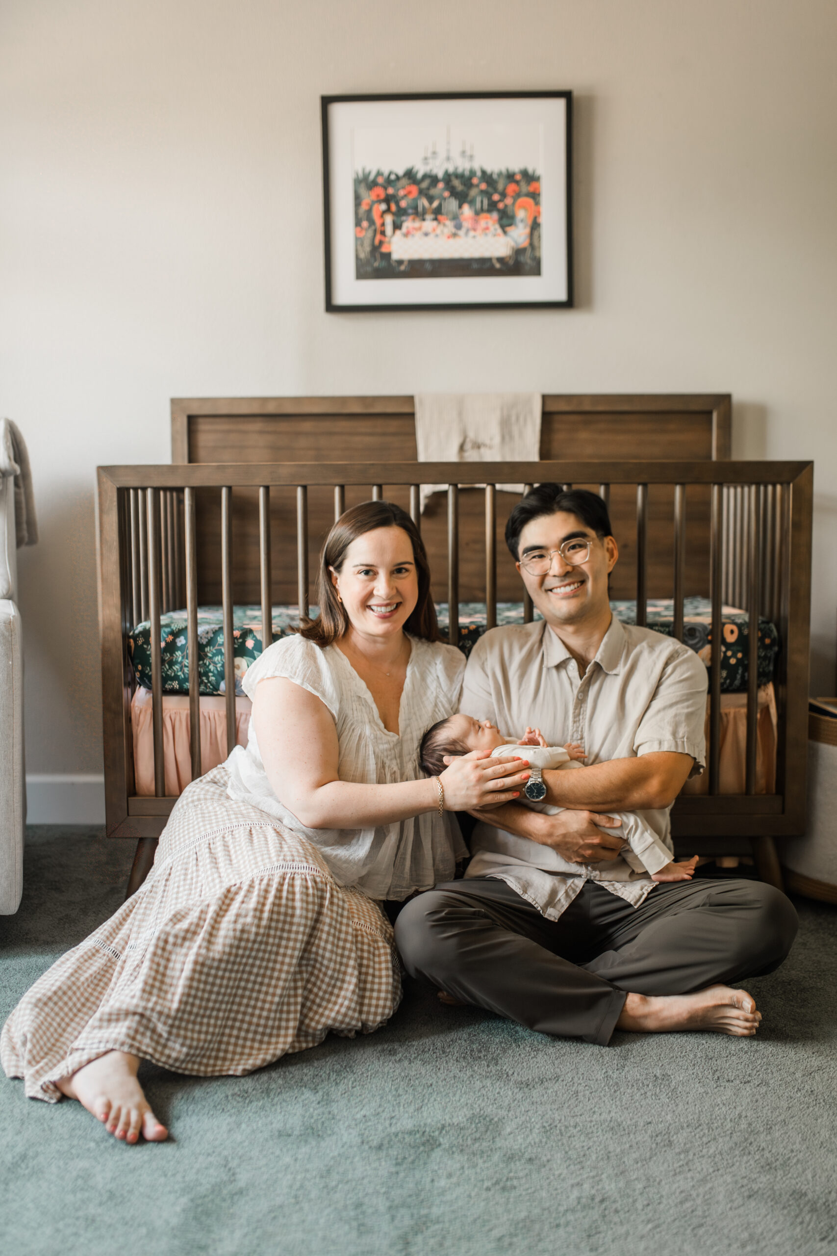 A beautiful Portland Oregon newborn photo session featuring two loving parents holding their baby girl in front of her crib.