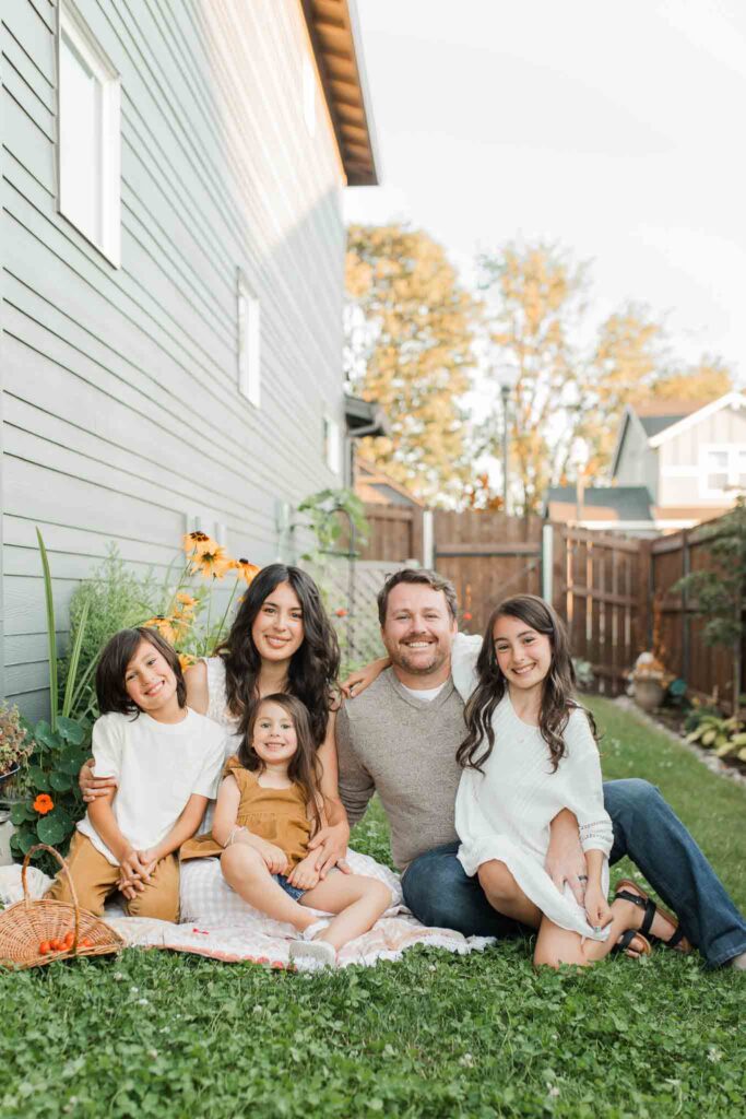 Backyard family photo in Vancouver WA of children harvesting strawberries and tomatoes with parents.