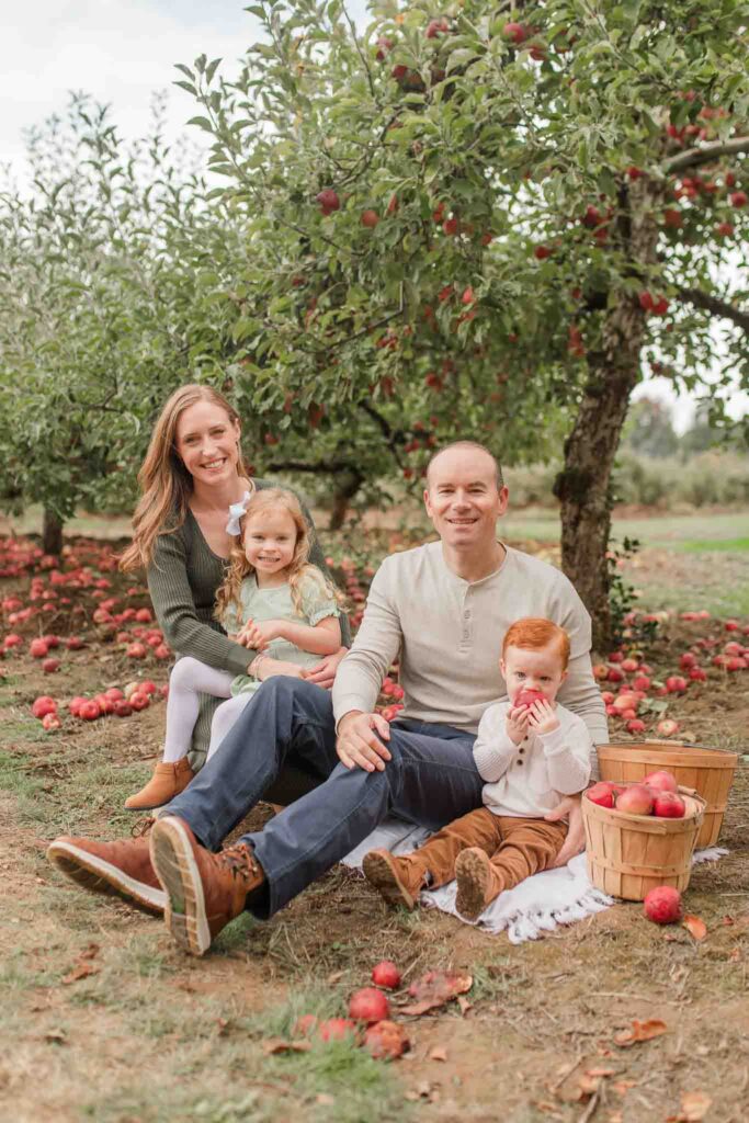 Family enjoying an apple orchard session in Camas WA, picking apples and snuggling on a blanket.