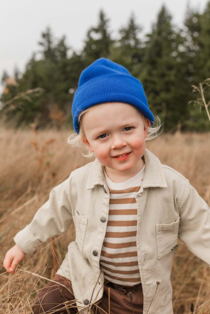 Candid moment of a parent chasing a toddler through a sunlit fall field, capturing genuine laughter in outdoor family photos.