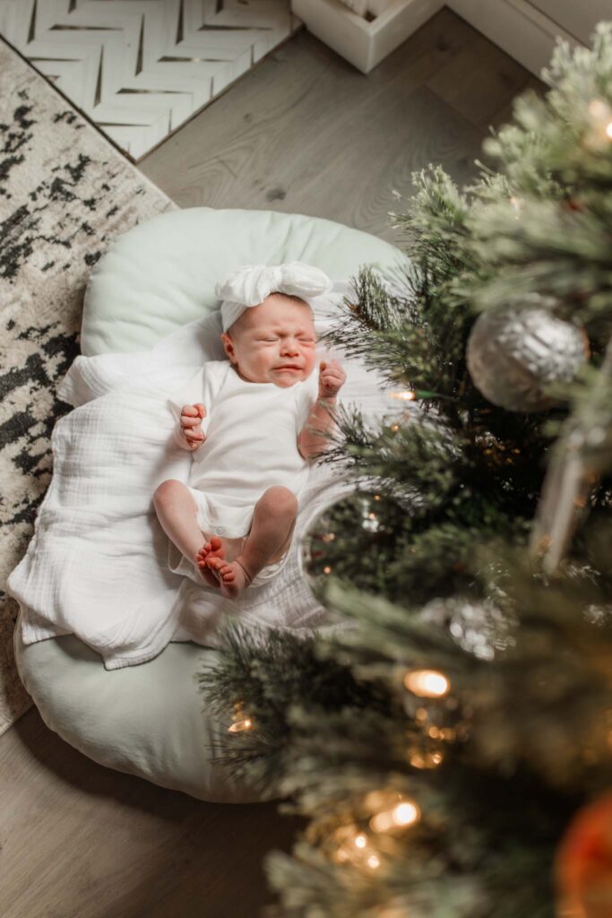 In-home newborn photo by Christmas tree in Vancouver WA