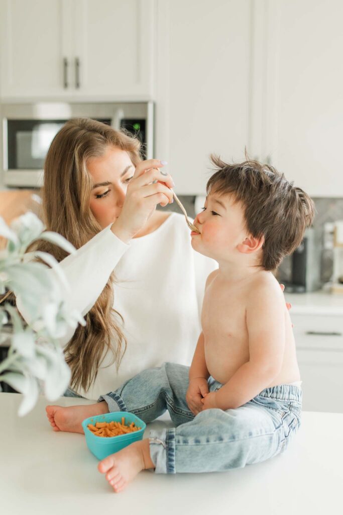 toddler eating mac and cheese in home during a lifestyle session in Vancouver WA