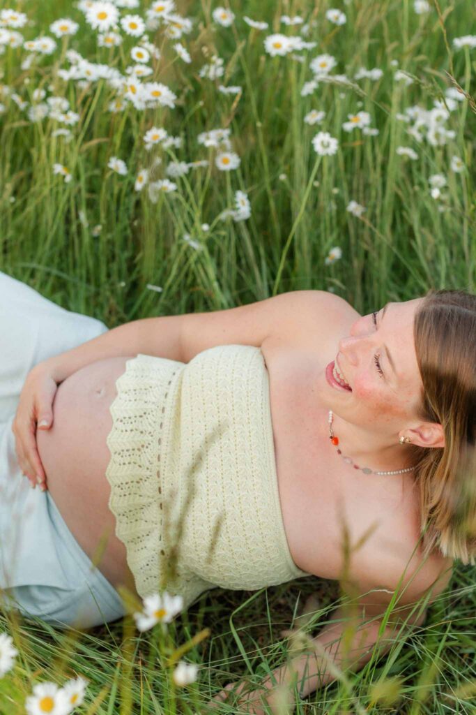 Expecting mother smiling in golden light during a natural outdoor maternity session with a Camas WA maternity photographer.