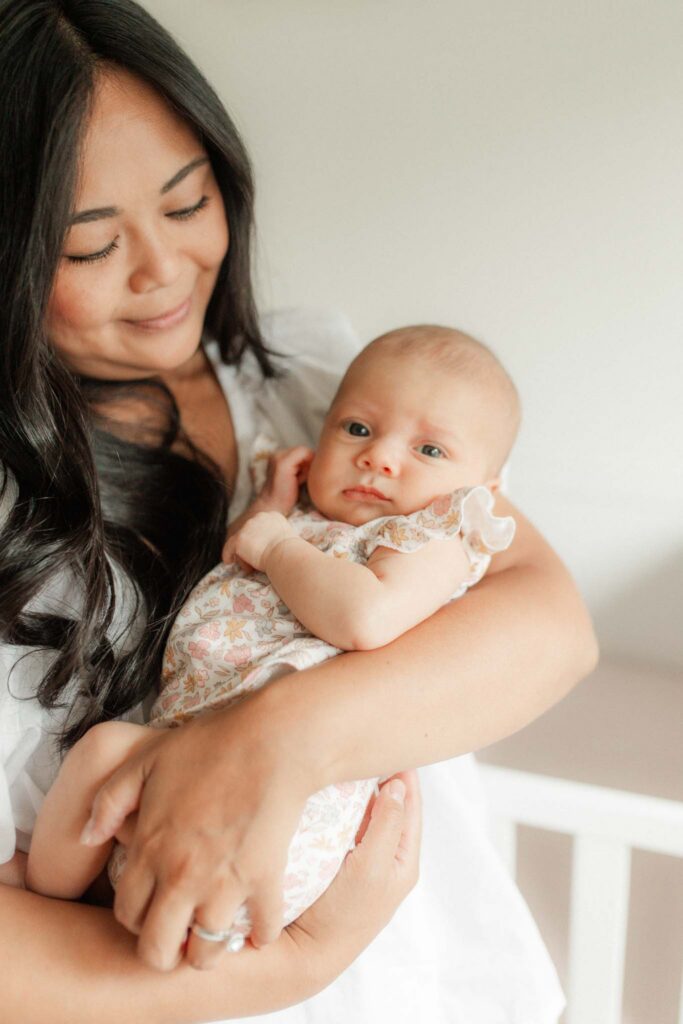 Washougal WA in-home newborn photographer capturing mother cuddling her newborn baby in a bright nursery