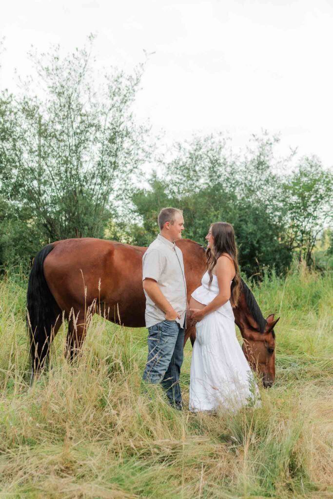 Expecting parents walking through tall golden grass during an outdoor maternity session