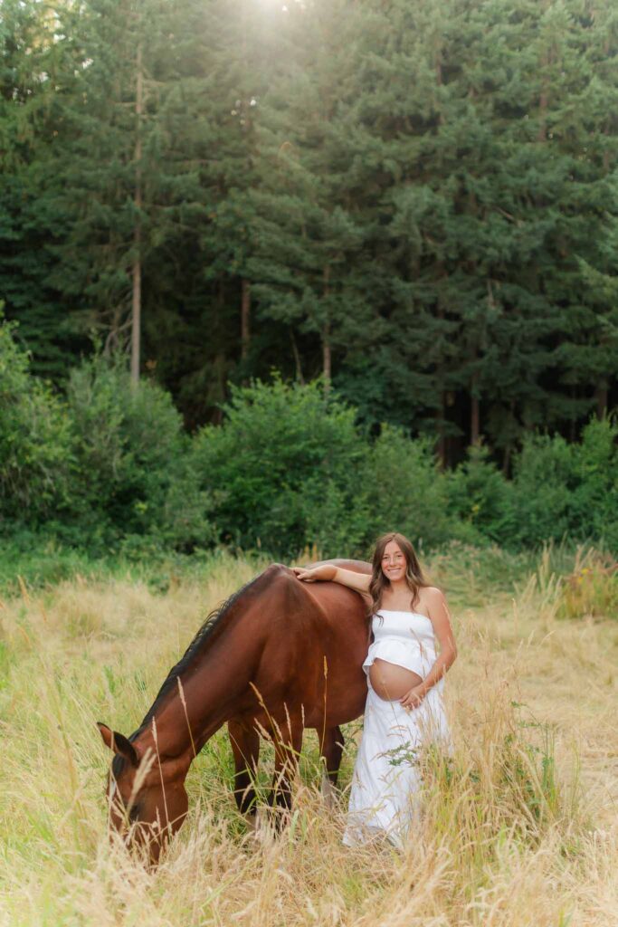 Pregnant mother gently petting her horse during maternity photos in a golden field
