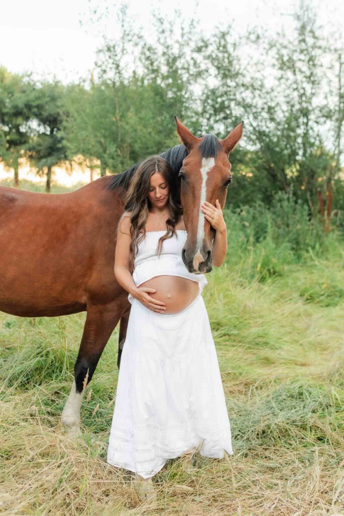 Expecting mother standing beside her horses during a western-inspired maternity photo session