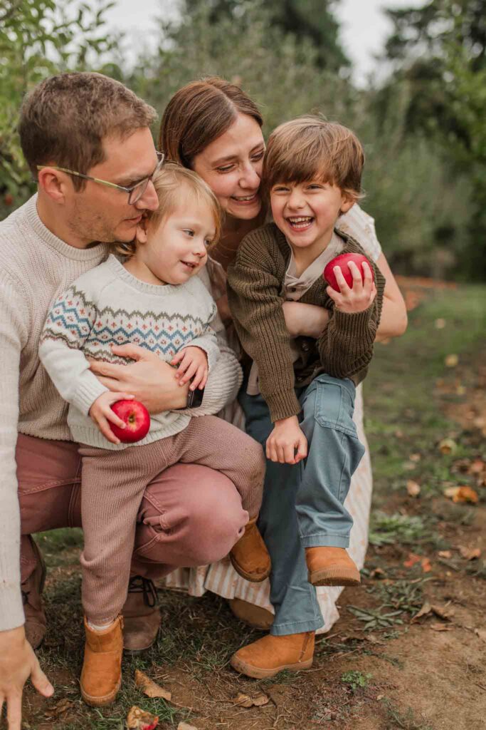 family of four dressed with fall family outfit inspiration for apple orchard mini sessions